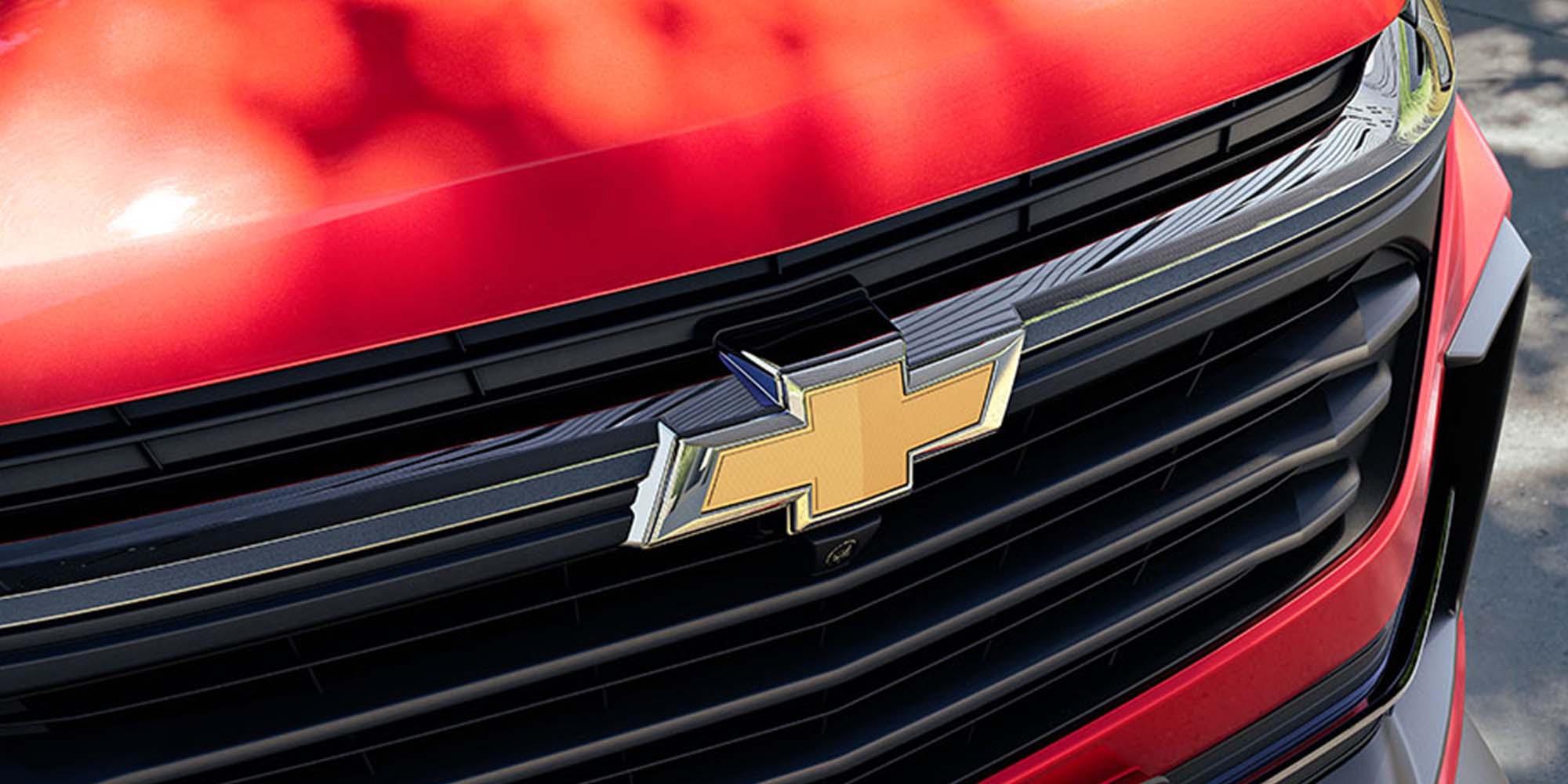 Logo y parte frontal de un carro Chevrolet color rojo