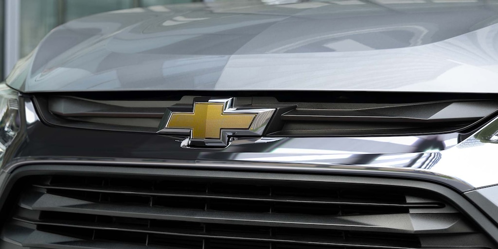 Logo y parte frontal de un carro Chevrolet color gris